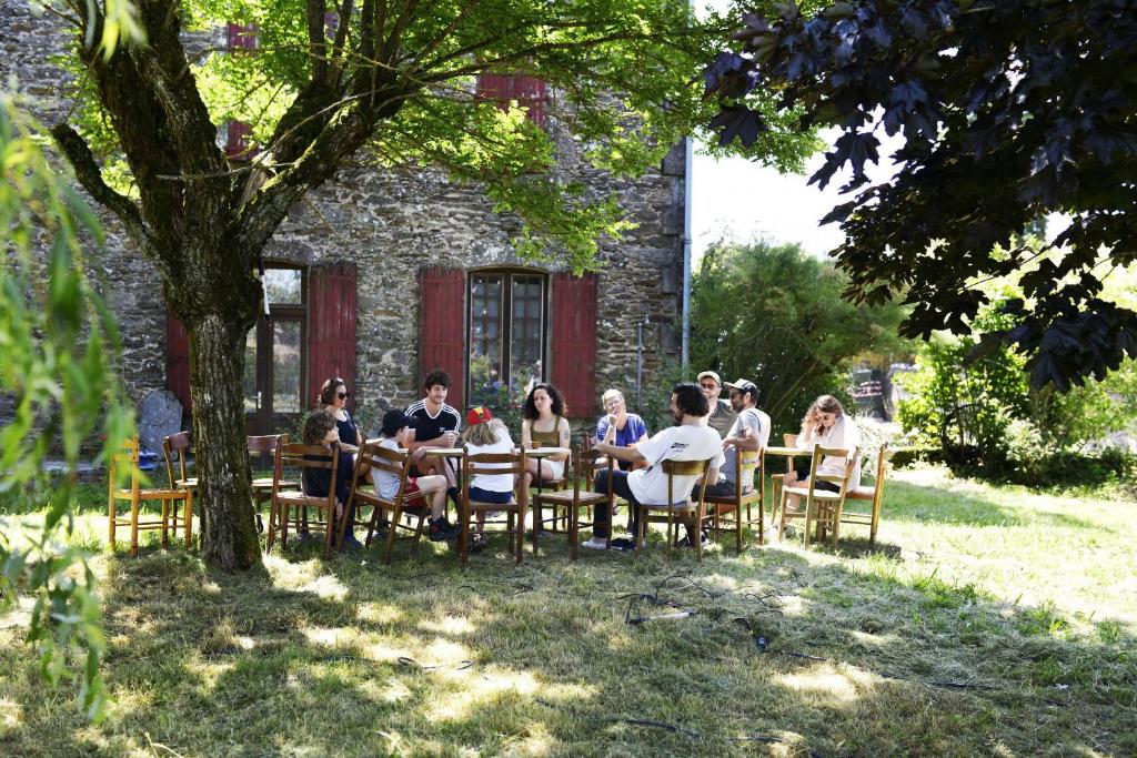 een groep mensen die aan een tafel voor een gebouw zitten bij La Villa Bouloc, gite pour la famille in Salles-Curan