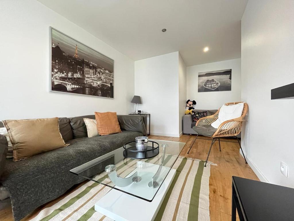 a living room with a couch and a glass table at Appartement la défense Courbevoie in Courbevoie