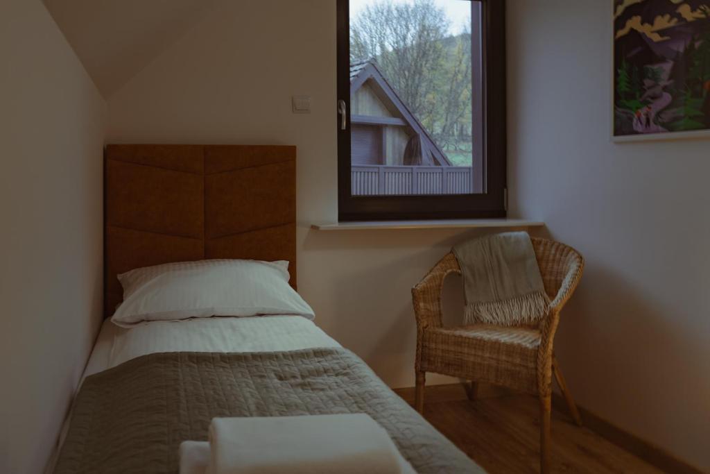 a bedroom with a bed and a chair and a window at Domek na szlaku in Szklarska Poręba