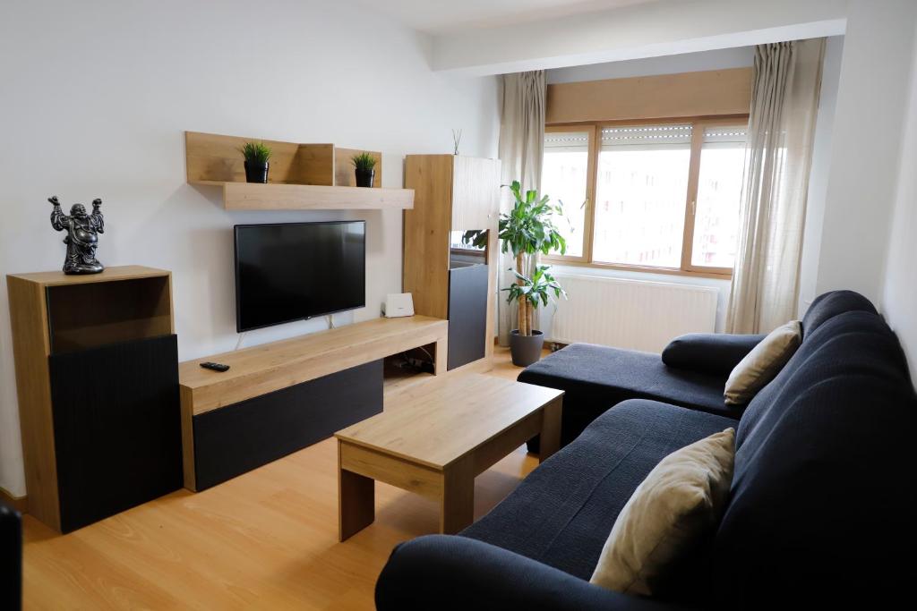 奧維多的住宿－ACOGEDOR Y LUMiNOSO，客厅配有蓝色的沙发和电视