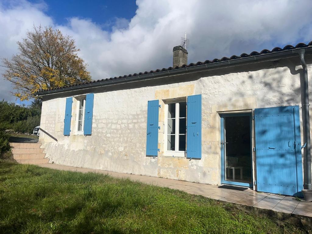 ein kleines weißes Gebäude mit blauen Fensterläden in der Unterkunft charmante maison de campagne in Jonzac