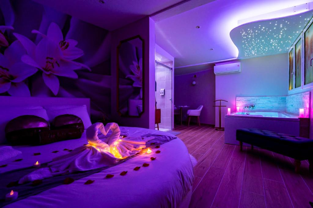 um quarto roxo com uma cama e uma banheira em Studio romantique jacuzzi ou spa balneo privatif et jardin Au temps des cerises La Ciotat em La Ciotat