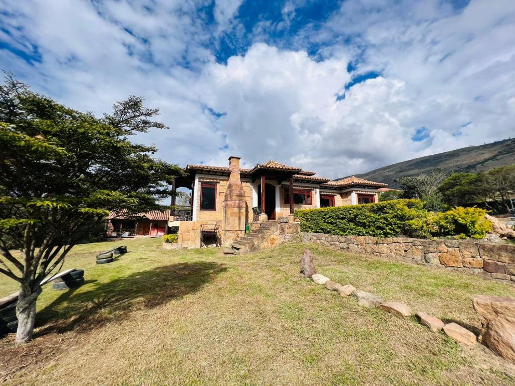a house with a stone wall in the yard at Cabaña Casa Cantabria in Villa de Leyva