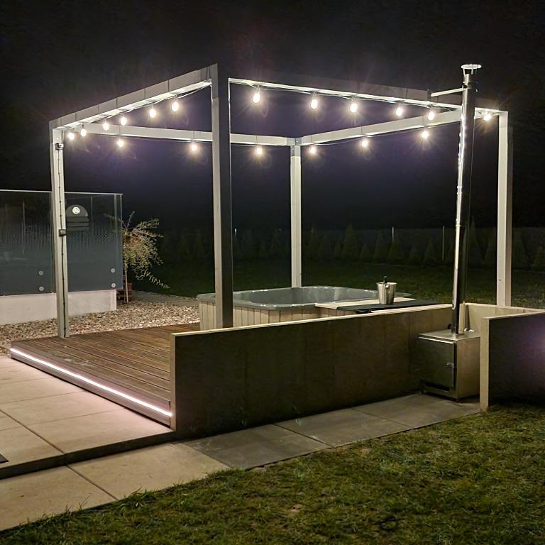 a lit up deck with a hot tub at night at Premium House Osztynek in Olsztynek