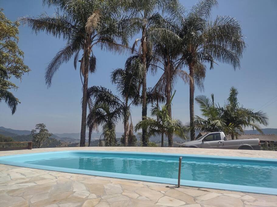 ein Schwimmbad mit Palmen und einem LKW in der Unterkunft Estância Martins in Extrema