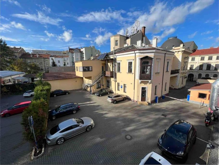 Un estacionamiento con autos estacionados frente a un edificio. en Palac Anežka A1, en Brno