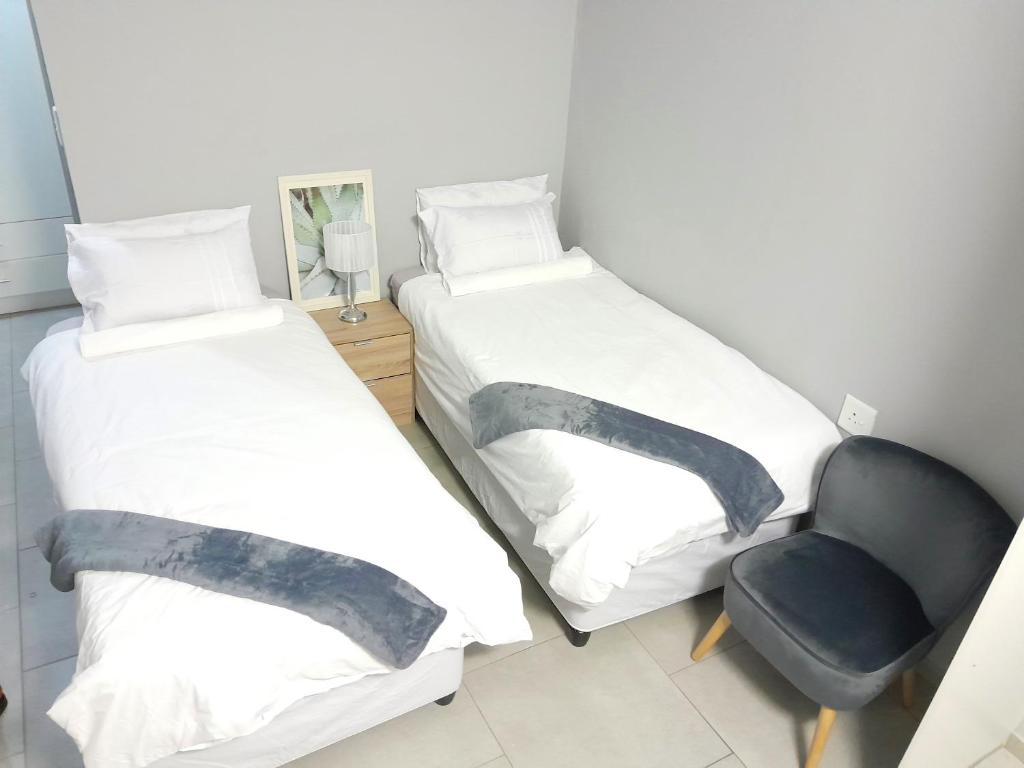 two beds and a chair in a room at White City Gardens, Empangeni, Ngwelezana in Empangeni