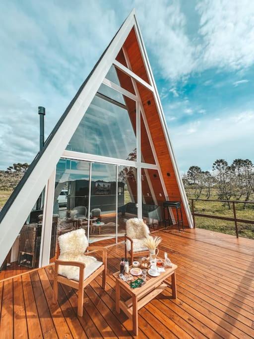 a wooden deck with two chairs and a table at Casa Di Legno Cabana com Spa, Ofurô e Vista para as Montanhas in Urubici