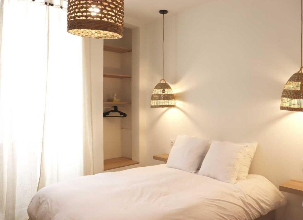 1 dormitorio con 1 cama blanca y 2 luces colgantes en Charmant studio en plein coeur de Tain l'Hermitage en Tain-lʼHermitage