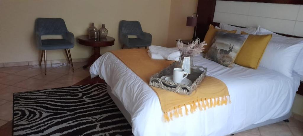 a bedroom with a large bed with two blue chairs at Marandela Guesthouse in Louis Trichardt