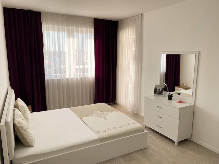 1 dormitorio con cama, tocador y espejo en City Center Apartment, en Ferizaj