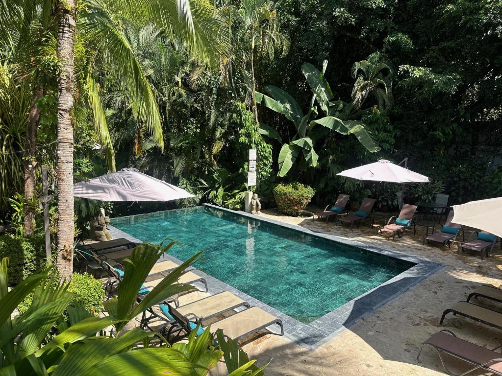 a pool with chairs and umbrellas in a resort at The Falls at Manuel Antonio in Manuel Antonio