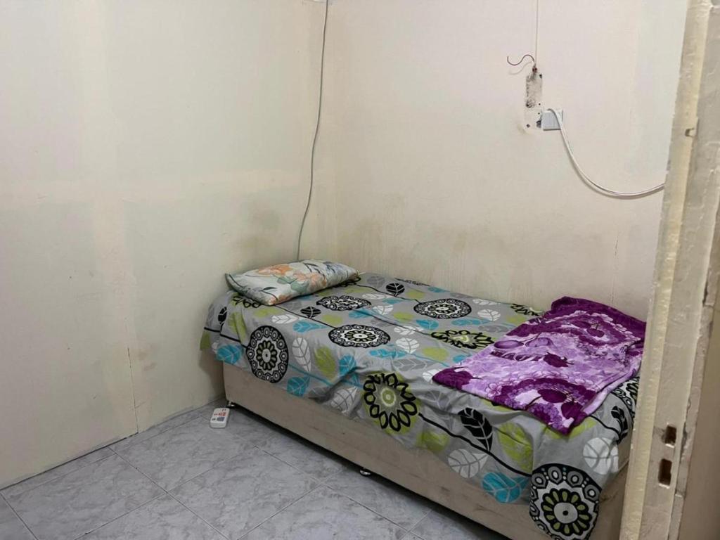 a small bed in a corner of a room at Regular homebased room in Sharjah