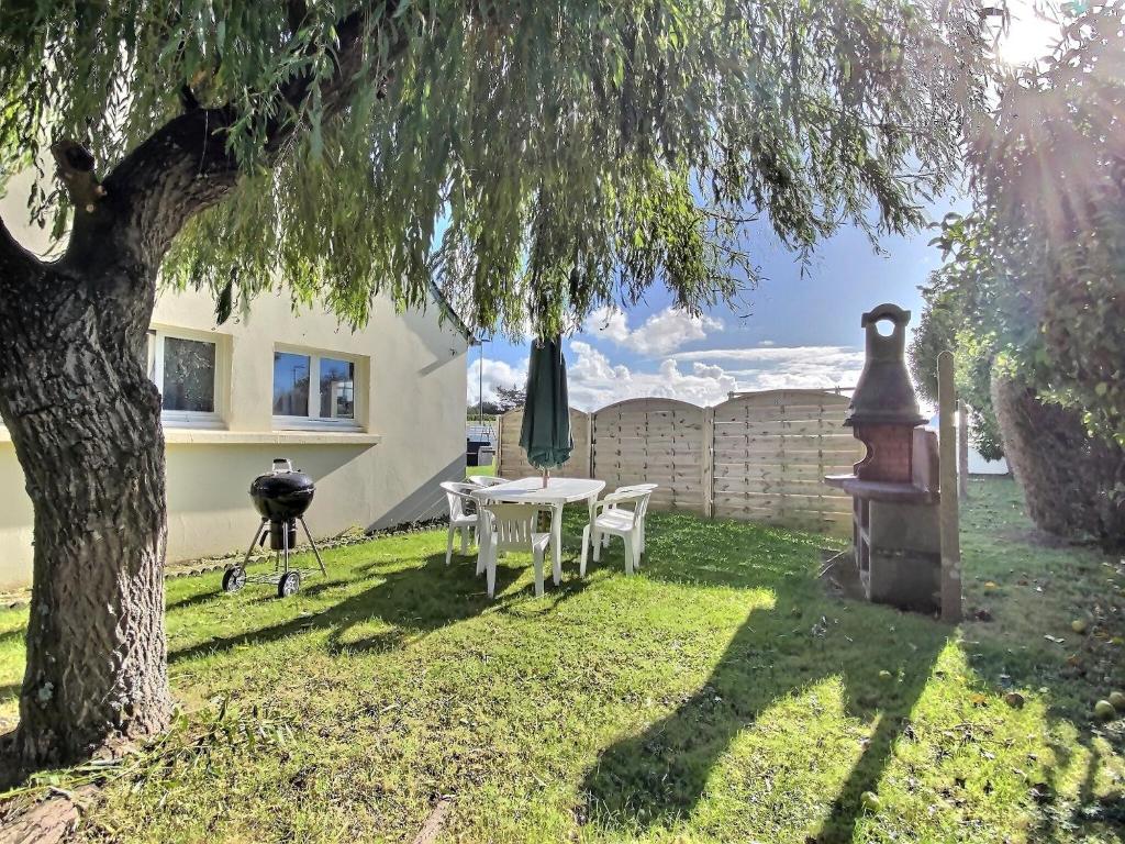 a yard with a table and a grill and a tree at Maison d'Ys à 500 m de la plage in Saint-Nic