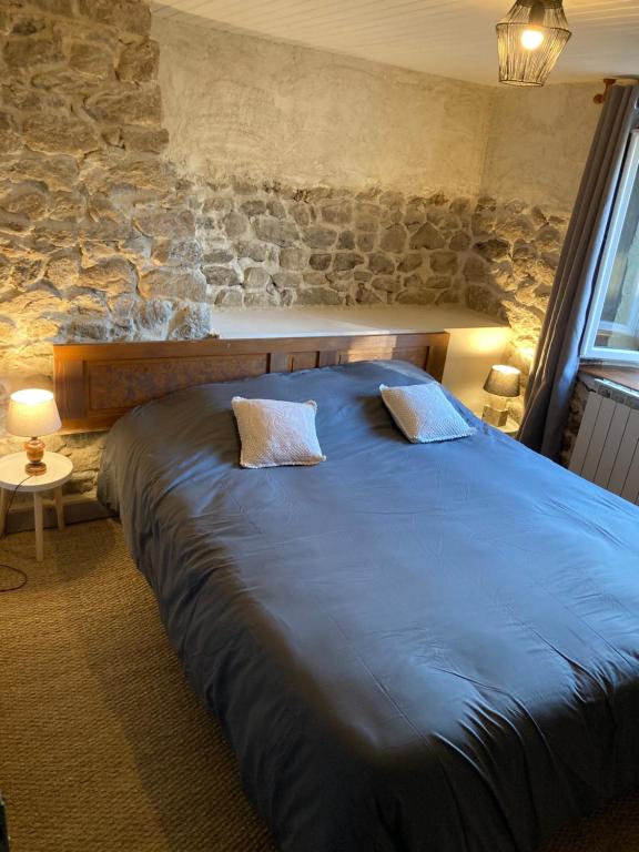 Una gran cama azul en una habitación con una pared de piedra. en Chez Élise et Jean Yves, en Job