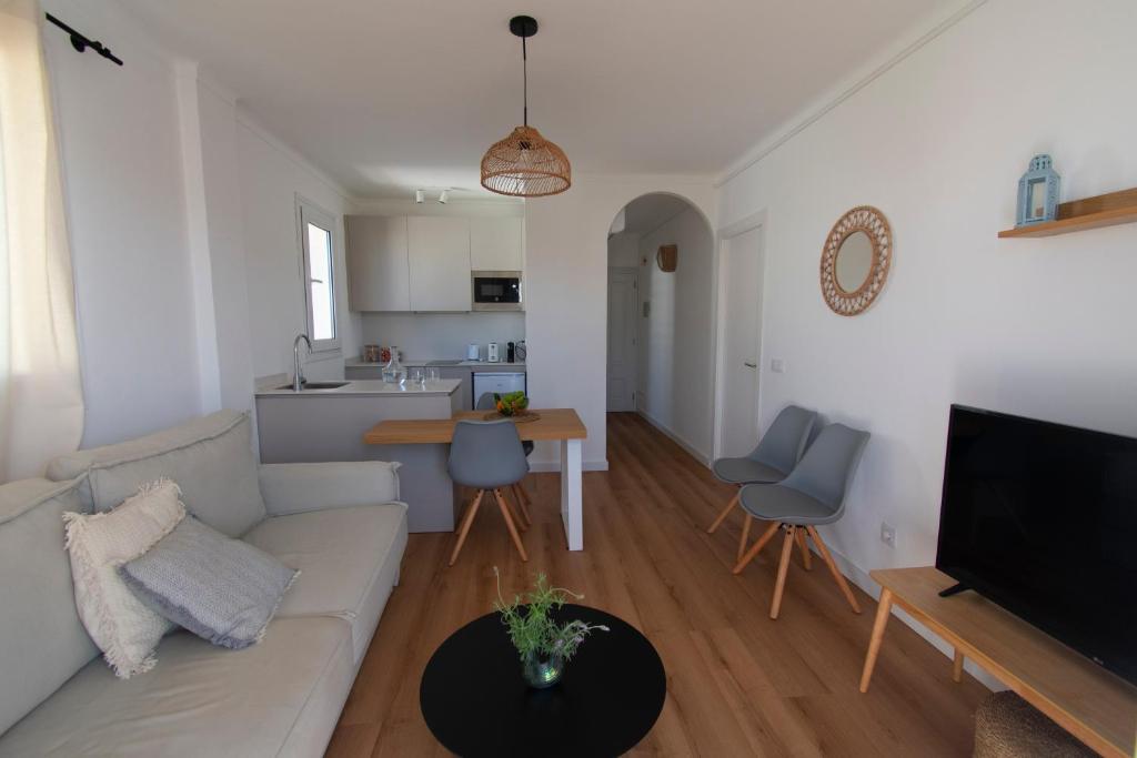 ein Wohnzimmer mit einem Sofa und einem Tisch sowie eine Küche in der Unterkunft Lavendel Apartments in Colonia Sant Jordi