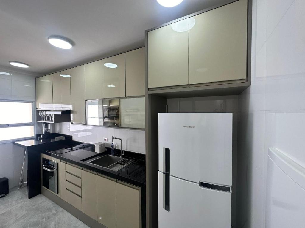 una cucina con frigorifero bianco e lavandino di Mar & Sol a Guarujá