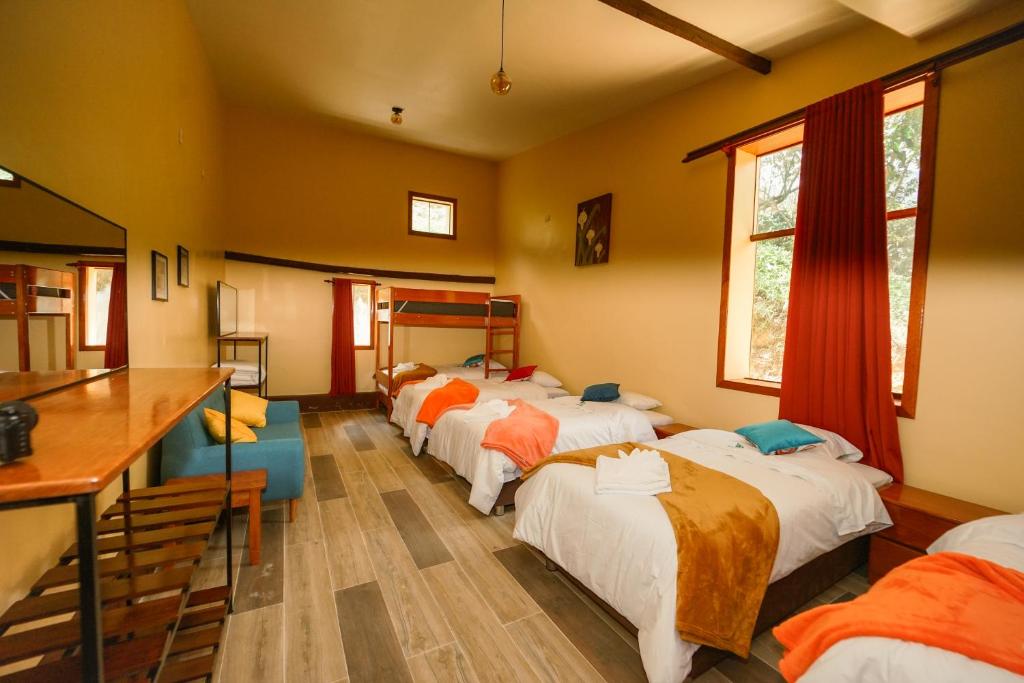 a group of beds in a room with a table at Ecoterra Inka Lodge in Quillabamba
