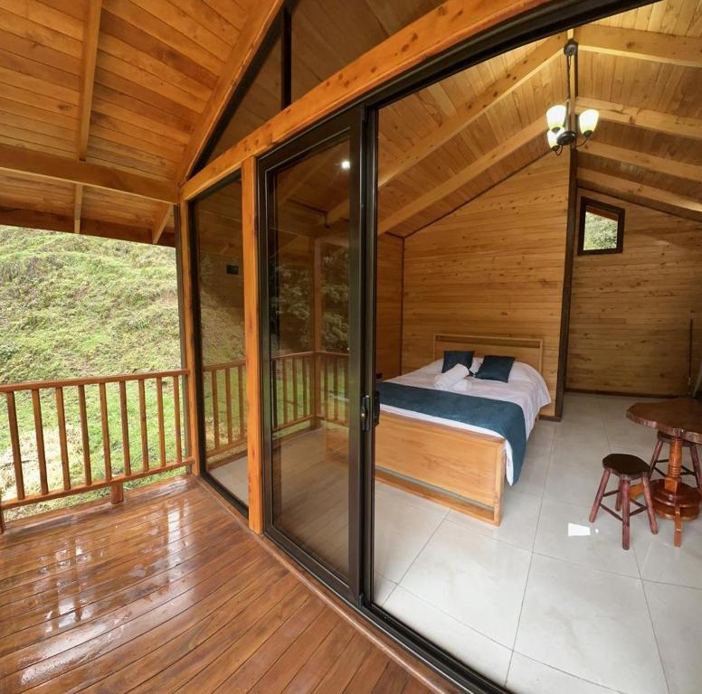 a bedroom in a cabin with a bed on a balcony at Chalet Amauleza in San Gerardo de Dota