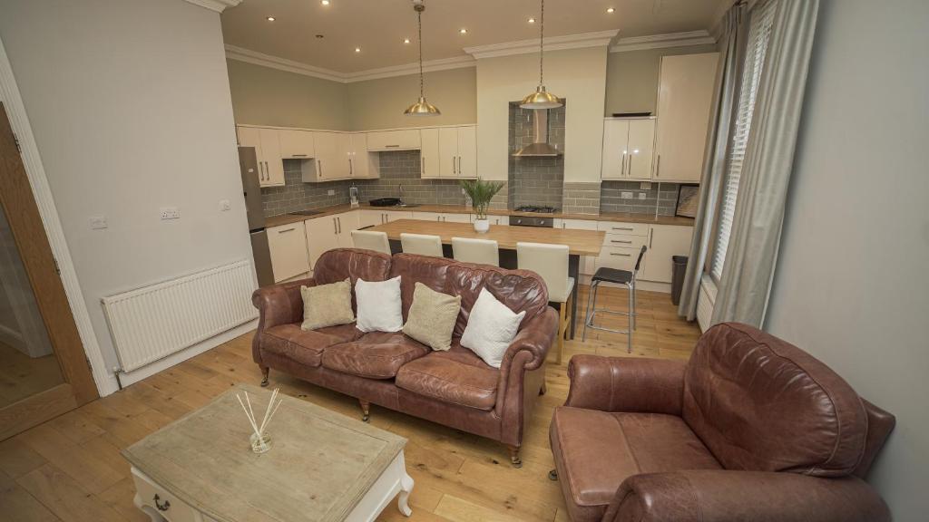 uma sala de estar com dois sofás de couro e uma cozinha em Central 4 Bed Apartment em Leeds