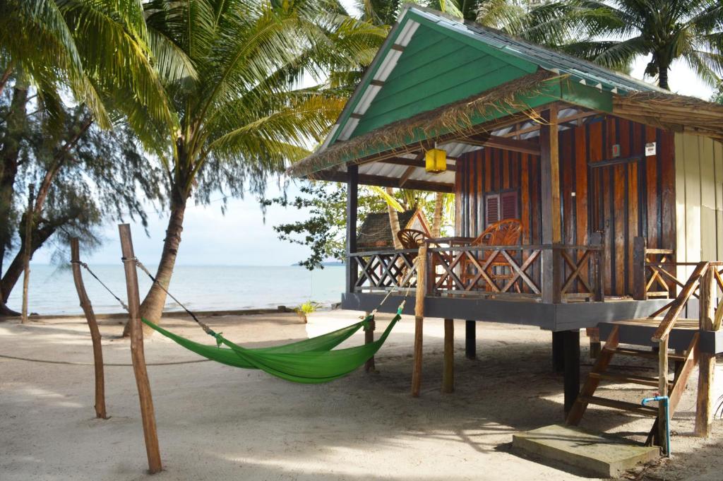 a hammock in front of a house on the beach at Palm Beach Bungalow Resort in Koh Rong Island
