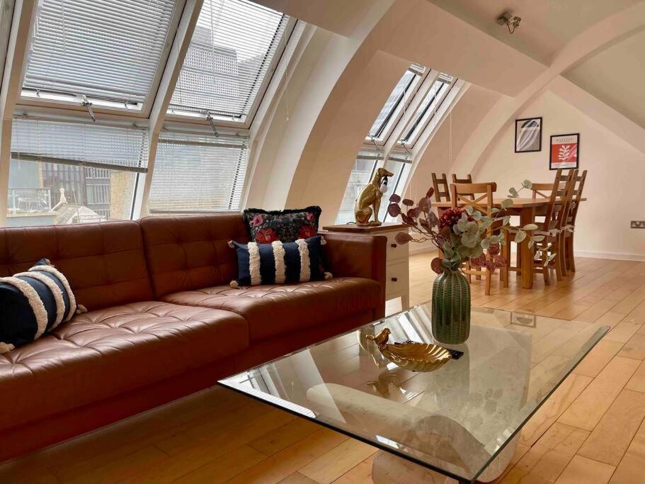 een woonkamer met een bruine bank en een glazen tafel bij Shad Thames by condokeeper in Londen