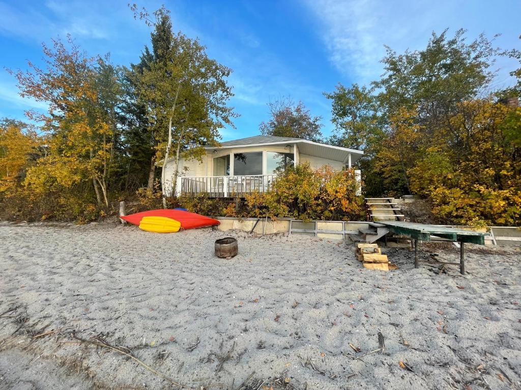 a house on the beach with a surfboard and a bench at NTJ Moose Lake Cabin in Bonnyville