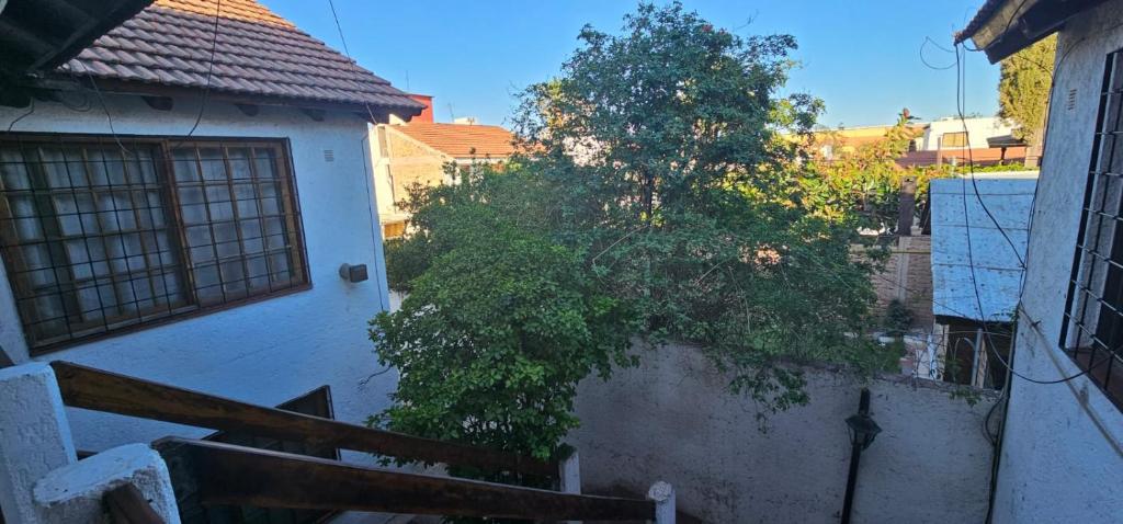 a tree next to a white building with a staircase at Departamento Erlich in Godoy Cruz