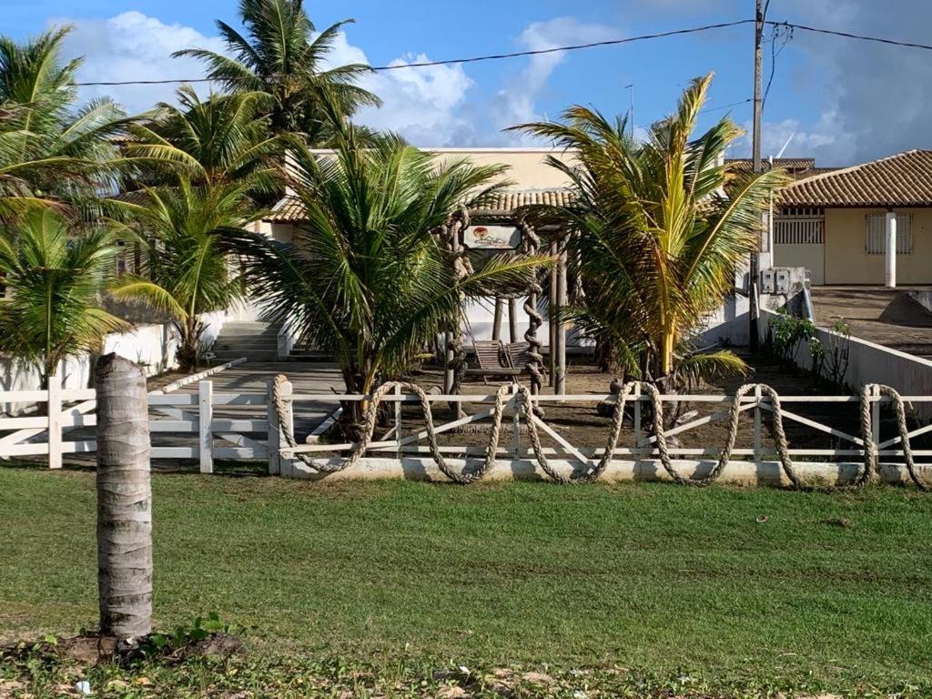 uma cerca em frente a uma casa com palmeiras em Casa de Praia - Aracaju - Jatobá em Barra dos Coqueiros
