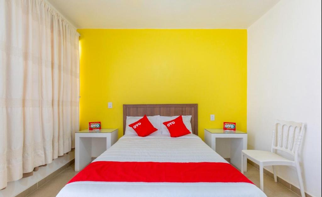 a bedroom with a bed with a yellow wall and red pillows at Hotel Rincón de los 3 Ángeles in Asunción Nochixtlán