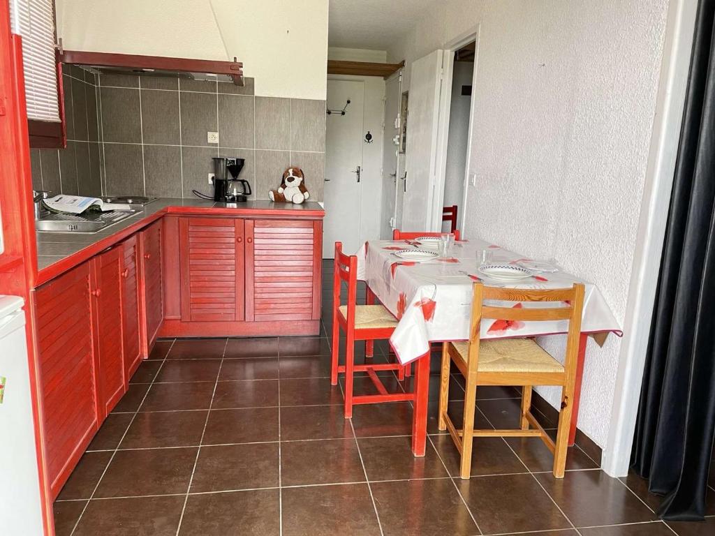 une cuisine avec des armoires rouges et une table et des chaises dans l'établissement Studio 5 Pers. à 100m des Pistes, Balcon N/O, Proche Commerces - Risoul 1850 - FR-1-330-570, à Risoul