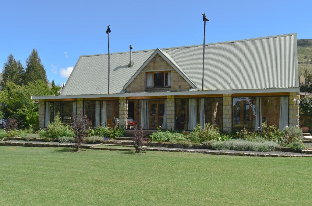 uma casa com um telhado de gambrel e um quintal em The Clarens Country House em Clarens