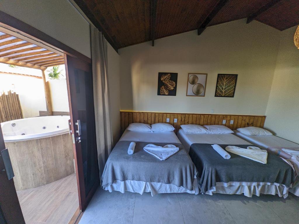 a bedroom with two beds and a bath tub at Pousada Lua Nova Pipa Chales com Hidromassagem e Jacuzzi in Pipa