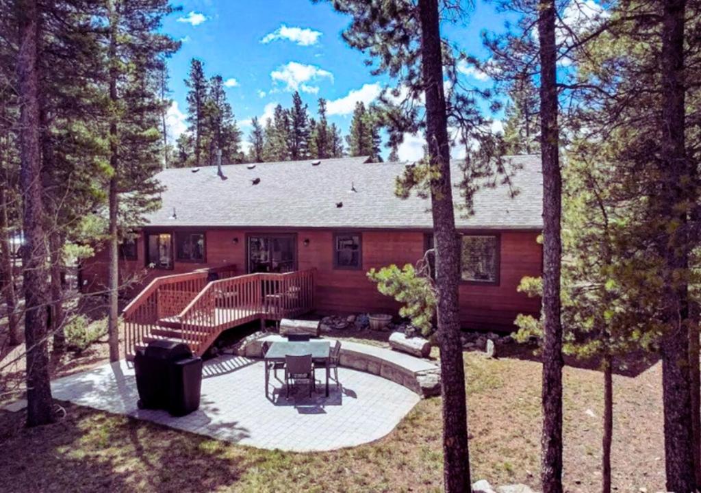 a log cabin with a deck in the woods at Pine Tree Lodge in Black Hawk