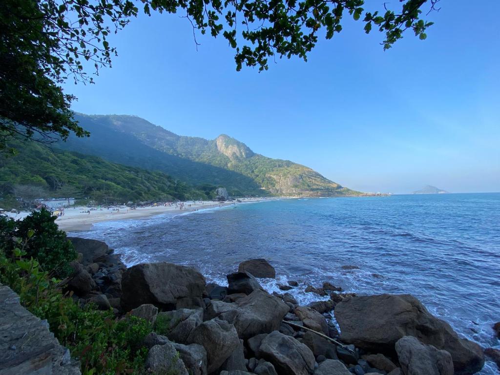 a beach with rocks and people on the beach at Conforto na Praia do Pontal in Rio de Janeiro