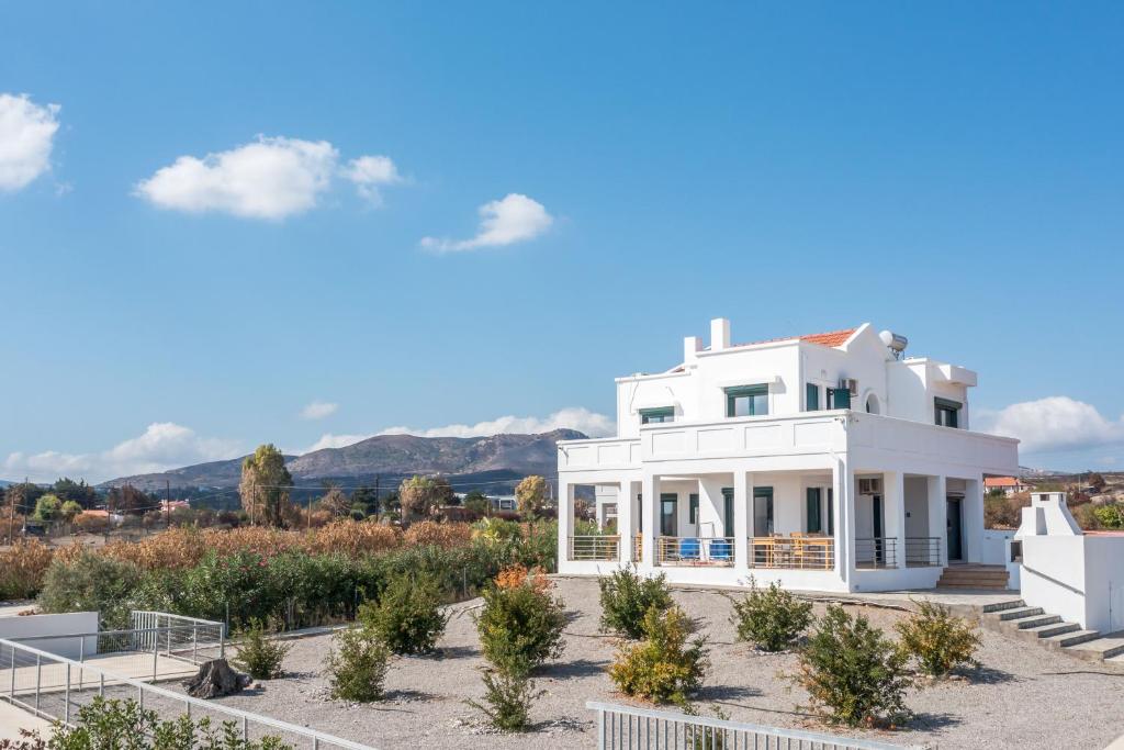 a white house with a garden and mountains in the background at Kelly's Beach House 2 in Gennadi