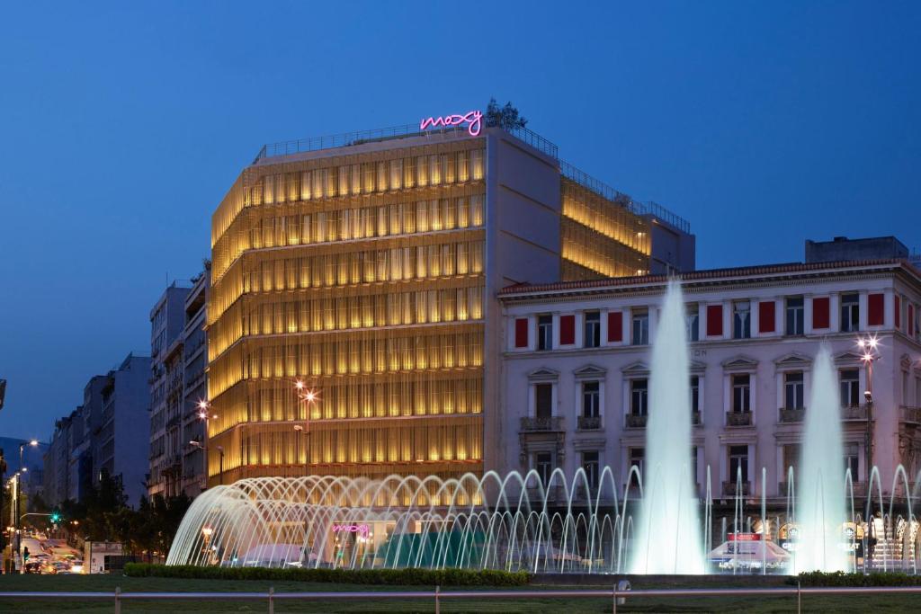 un bâtiment avec une fontaine en face d'un bâtiment dans l'établissement Moxy Athens City, à Athènes