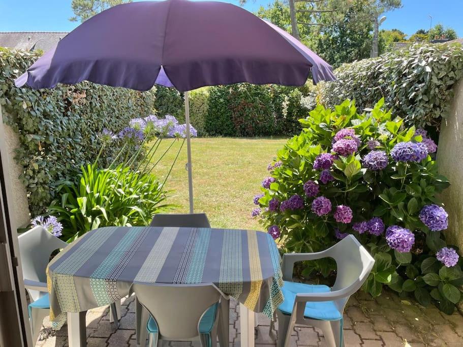 une table et des chaises avec un parasol et des fleurs dans l'établissement L'appartement de la Garenne, à Carnac