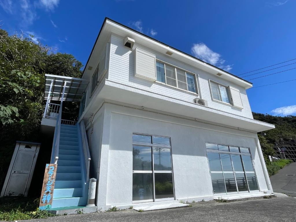 una casa blanca con una escalera azul delante de ella en 神津島民宿菊乃屋～きくのや～kikunoya, en Kōzushima