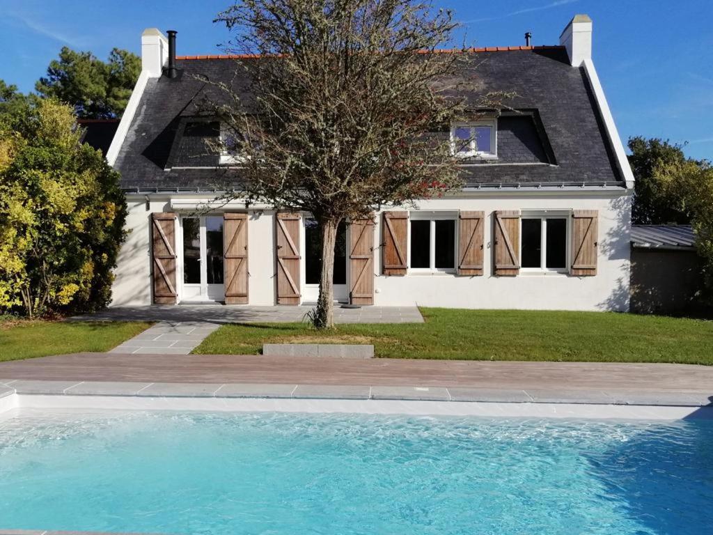 uma casa com piscina em frente a uma casa em Jolie Villa avec piscine chauffée 8 par 4 m em Erdeven