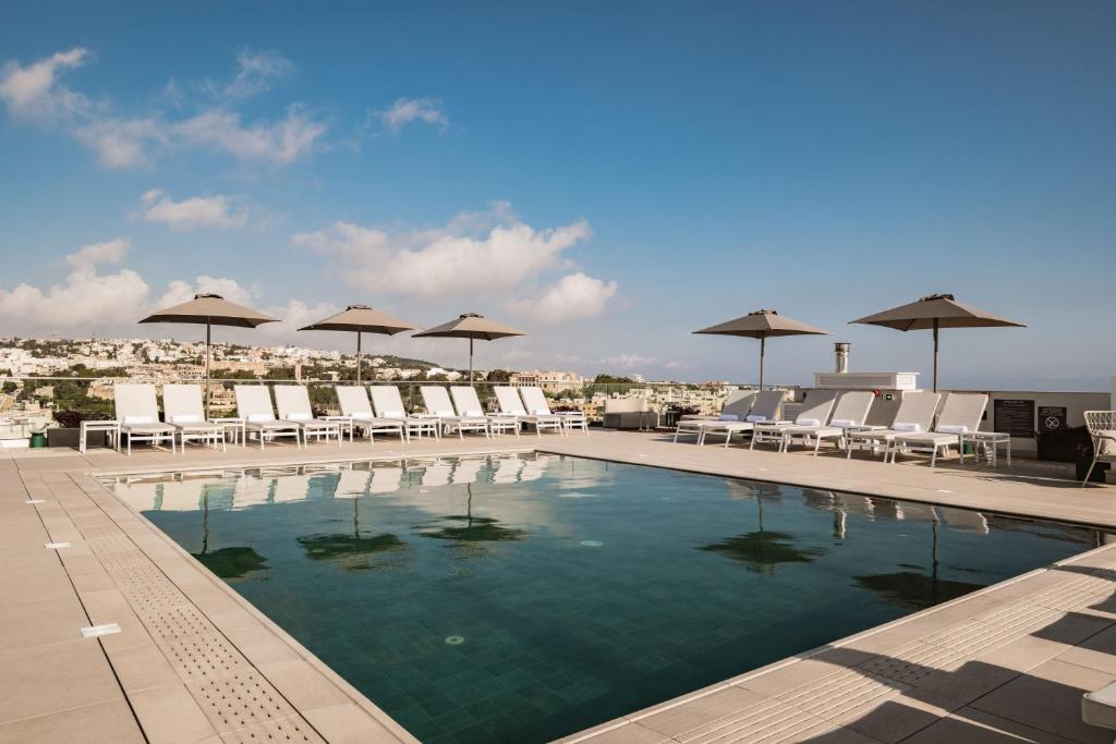 a swimming pool with chairs and umbrellas on a roof at AC Hotel by Marriott St Julian's in St Julian's