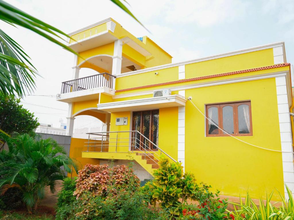 a yellow house with a balcony at Prabas - Farm house in Puducherry
