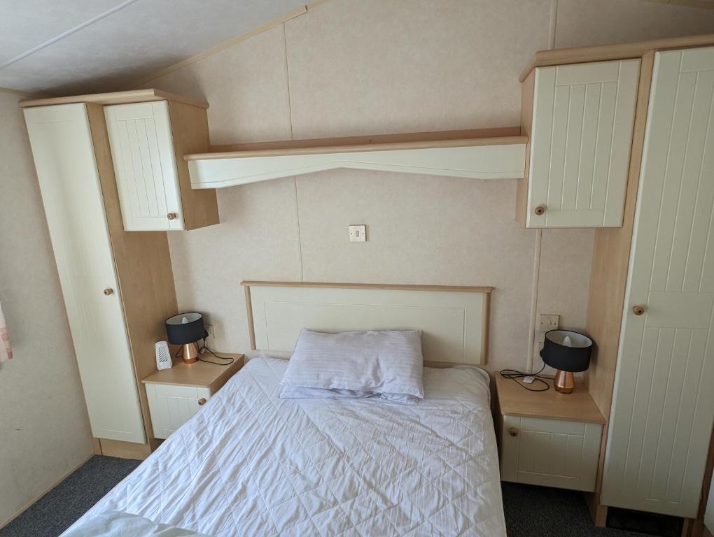 a small bedroom with a bed and two cabinets at Caravan in Kinmel Bay