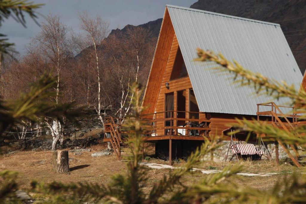 eine Blockhütte in den Bergen mit einer Terrasse in der Unterkunft AURA Cottages in Kazbegi