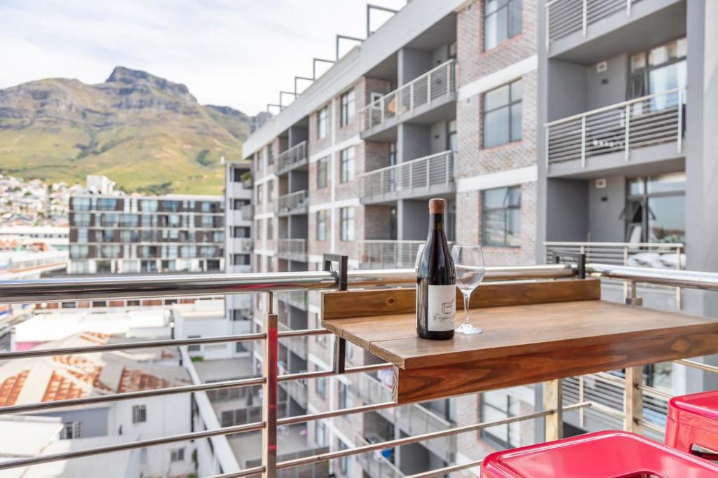 eine Flasche Wein auf einem Holztisch auf einem Balkon in der Unterkunft Mountain View Apartment at Woodstock Quarter in Kapstadt
