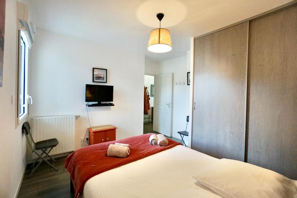um quarto com uma cama grande e um cobertor vermelho em Les sables blancs*50m de la mer* em Concarneau