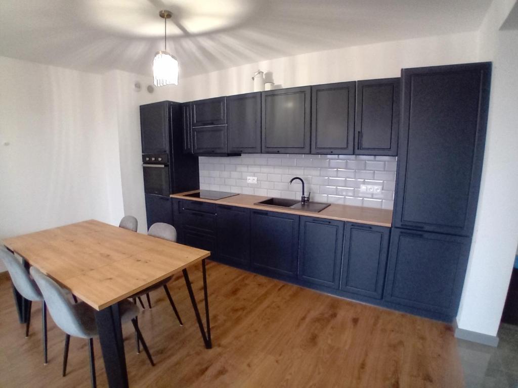 a kitchen with black cabinets and a wooden table at Apartament Na Wzgórzach in Rymanów