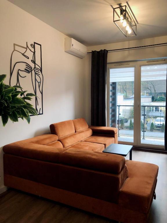 salon z brązową kanapą i oknem w obiekcie Green Stone Apartment III w Bydgoszczy