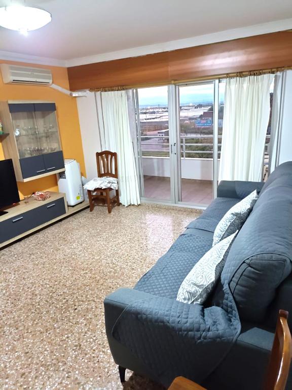 uma sala de estar com um sofá azul e uma televisão em Cómodo alojamiento muy cerca de la playa em El Perellonet
