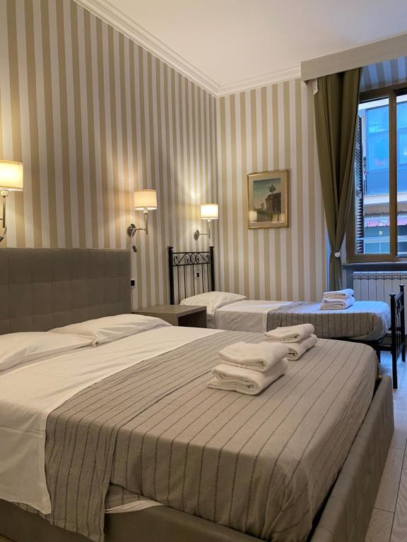 una camera d'albergo con due letti e asciugamani di Rome Orange Inn a Roma